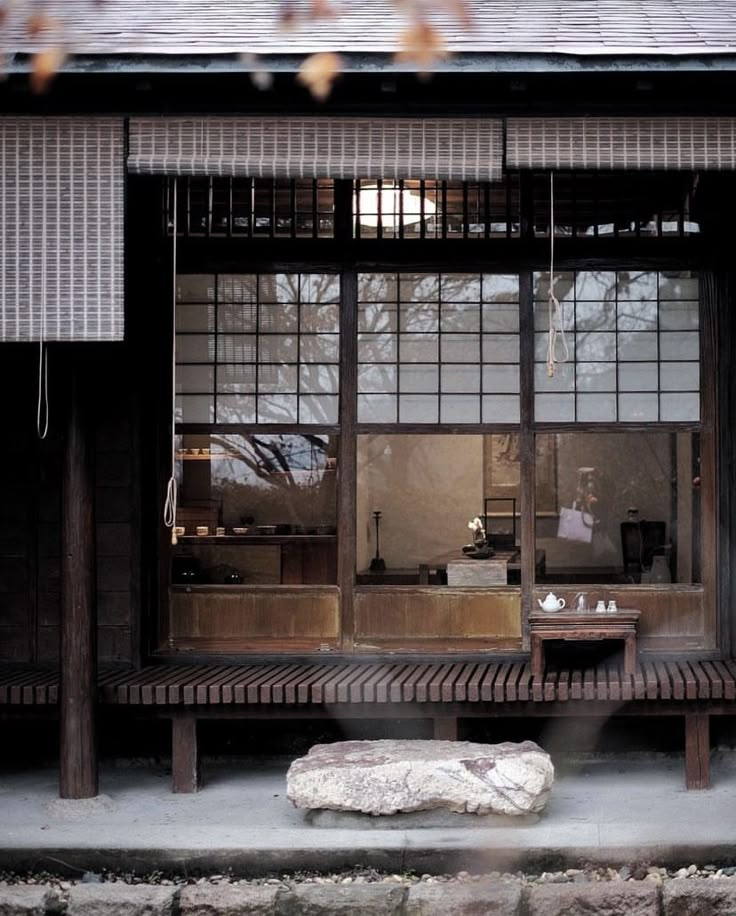 a bench sitting in front of a window next to a stone slab on the ground