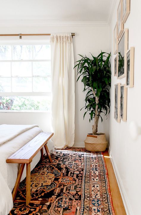 a bed sitting next to a window with a rug on the floor in front of it