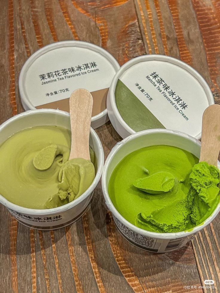 three bowls of green tea ice cream with wooden spoons in each bowl on a table