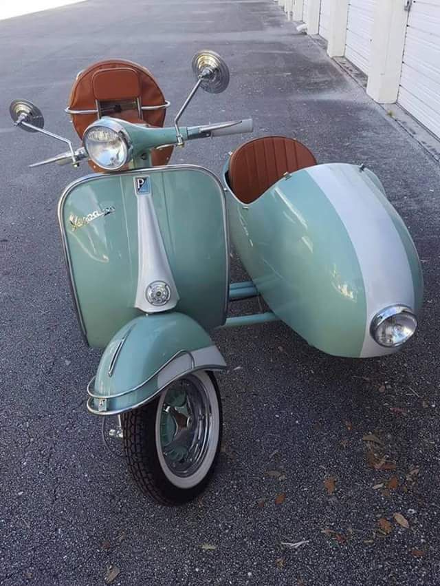 an old scooter is parked in a parking lot next to a garage door