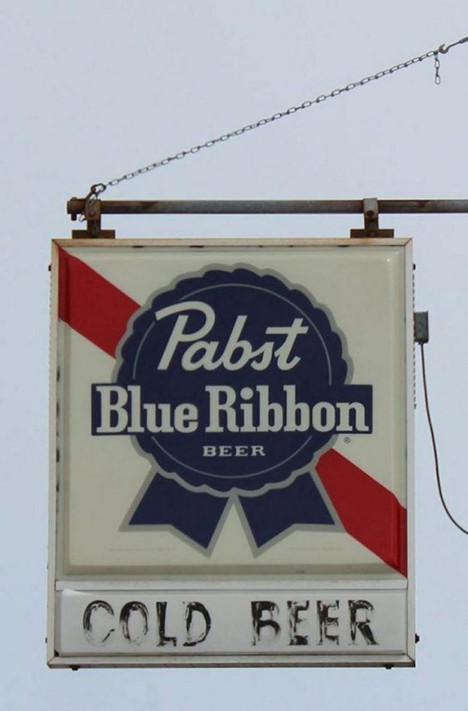 a sign hanging from the side of a building that says pub, blue ribbon beer