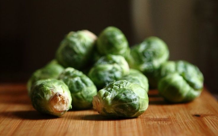 green brussel sprouts sitting on top of a wooden table