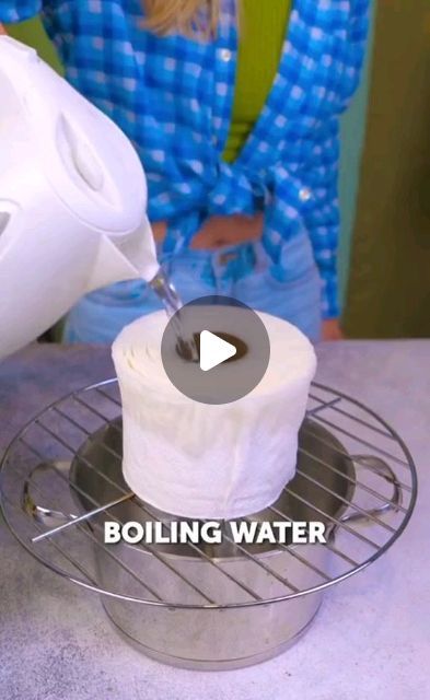 a woman is pouring water into a container with a roll of toilet paper on it