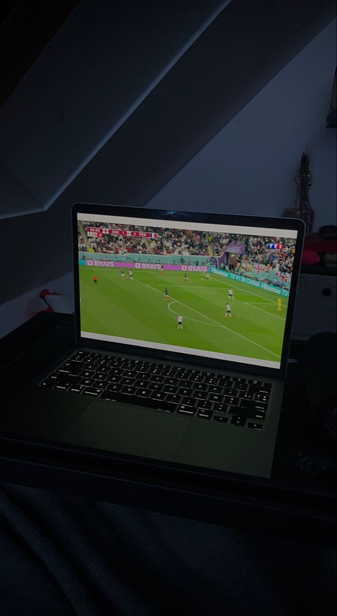 an open laptop computer sitting on top of a desk in front of a tv screen