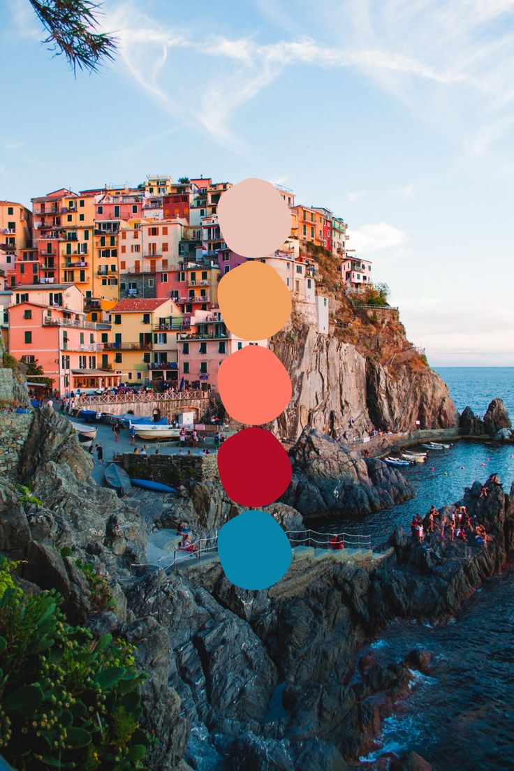 the colorful buildings are on top of the cliff by the water and people swimming in the ocean