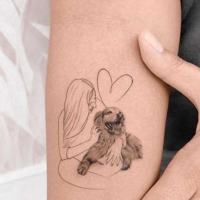 a woman holding a dog with a heart tattoo on her arm and behind her ear