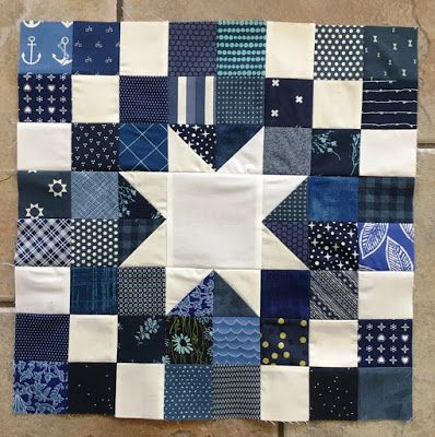 a blue and white patchwork quilt hanging on a wall with an anchor in the middle