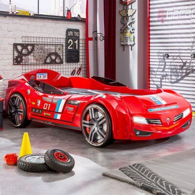 a red sports car parked in a garage next to a yellow cone and some tires