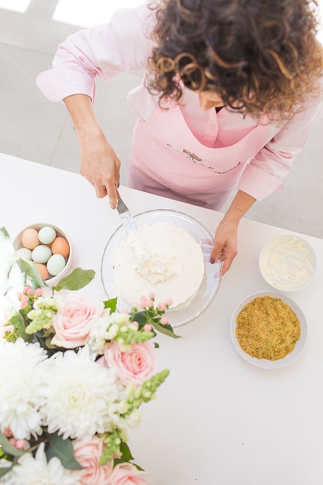 a woman is decorating a cake with flowers and eggs