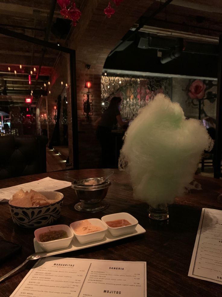 a table with food and drinks on it in front of a menu at a restaurant