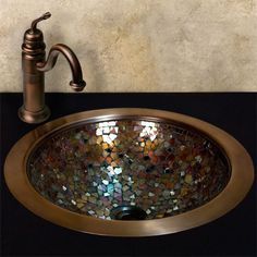 a bathroom sink that is made out of glass and copper colored tiles with a faucet