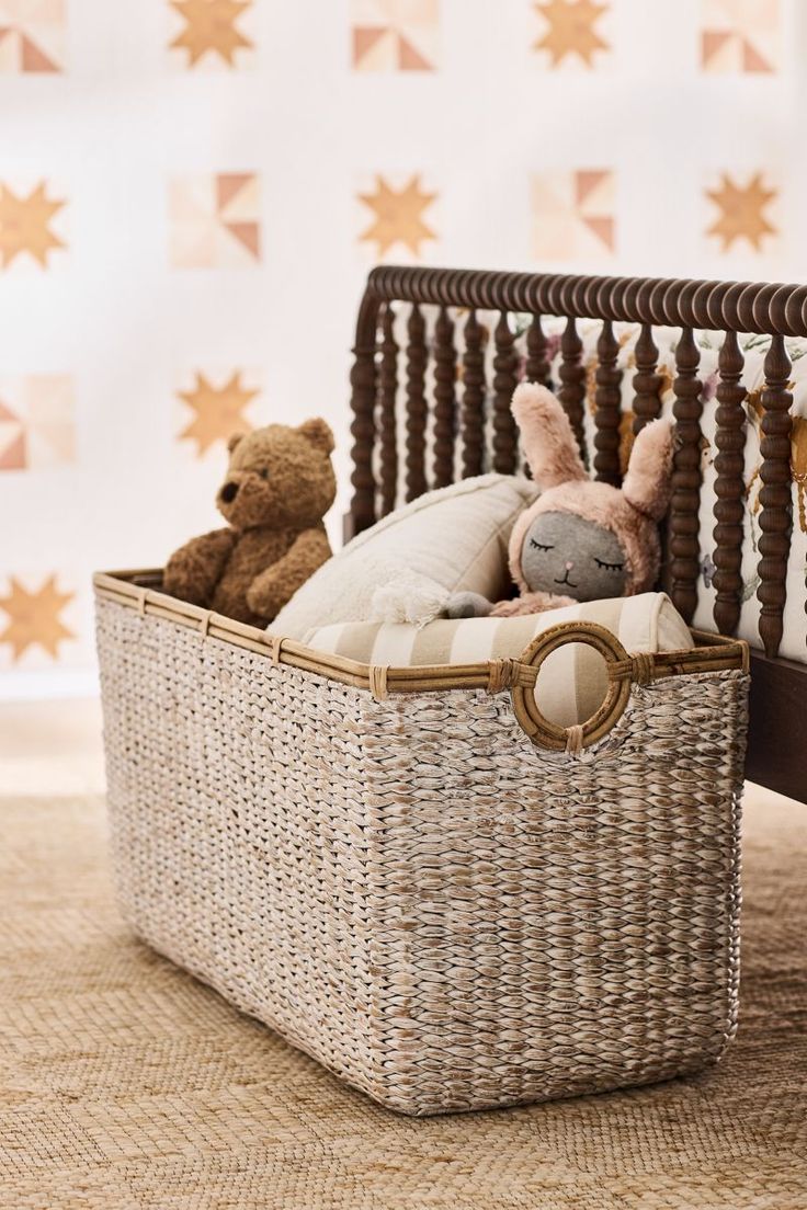 two stuffed animals in a wicker basket on the floor next to a crib