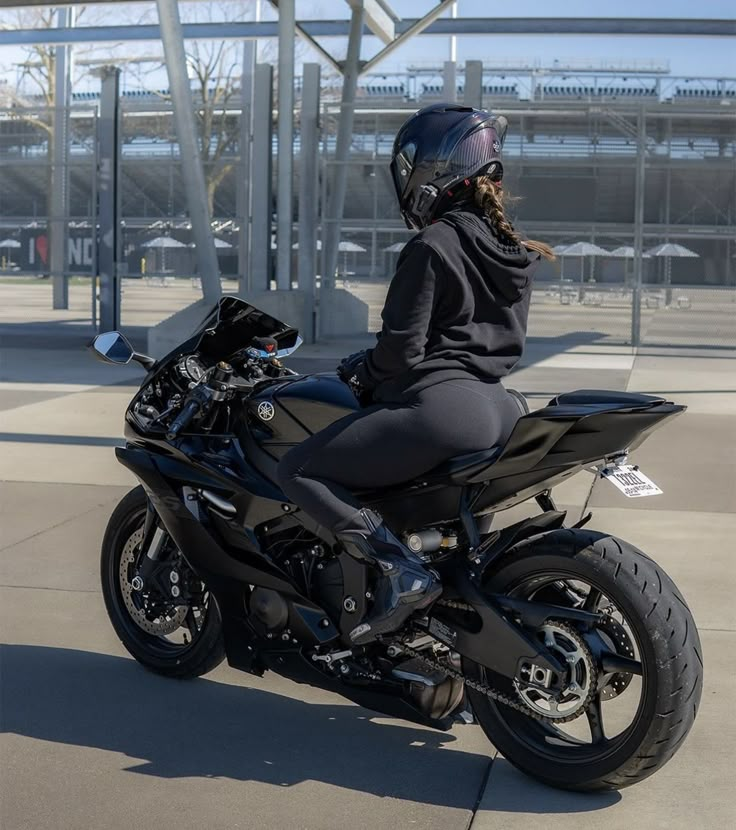 a person sitting on a motorcycle in front of a building with an open parking lot