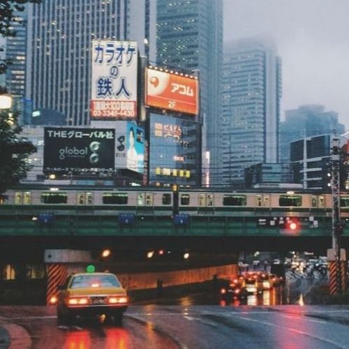 a busy city street at night with traffic and billboards on the buildings in the background