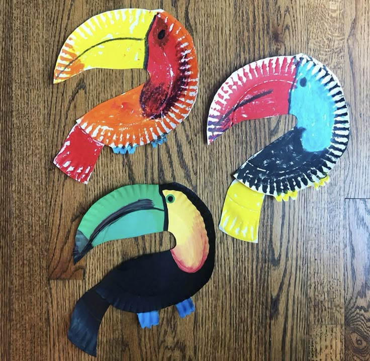 four paper plates shaped like toucans on a wooden table