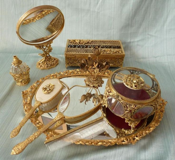 an assortment of gold and glass items on a white cloth covered table with a blue background