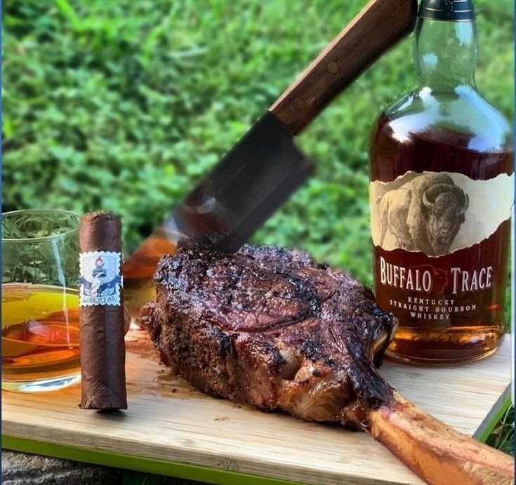 there is a steak on the cutting board next to some liquor