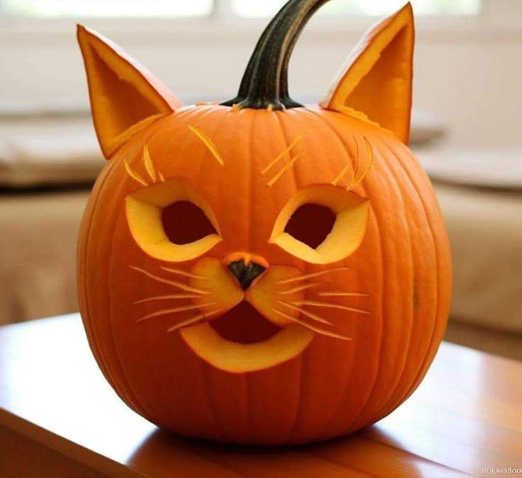 a pumpkin with a cat's face carved into it, sitting on a table