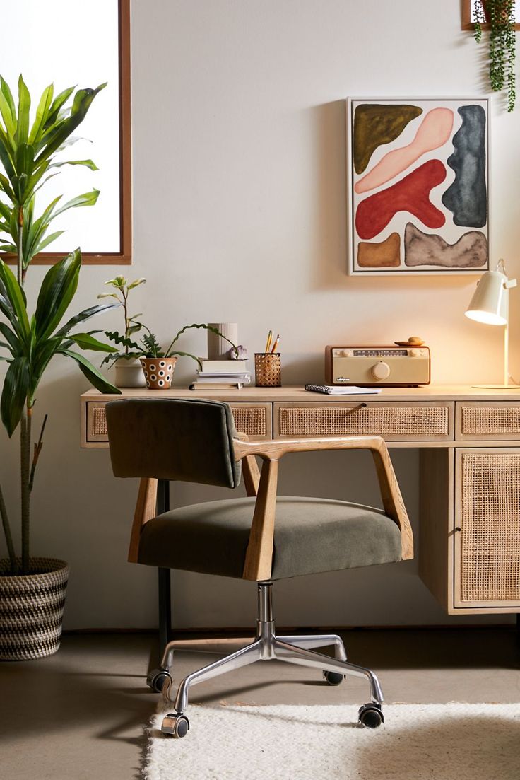 a desk with a chair, potted plant and pictures on the wall