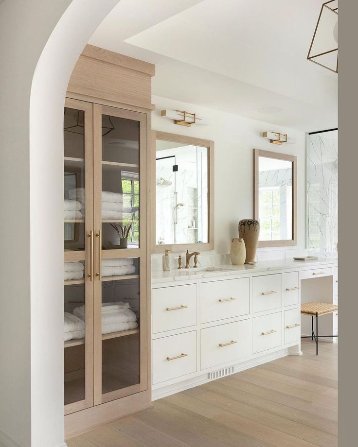 a large bathroom with white cabinets and marble counter tops, along with wooden flooring