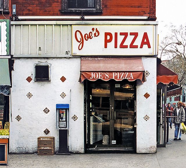 a pizza shop with people walking by it