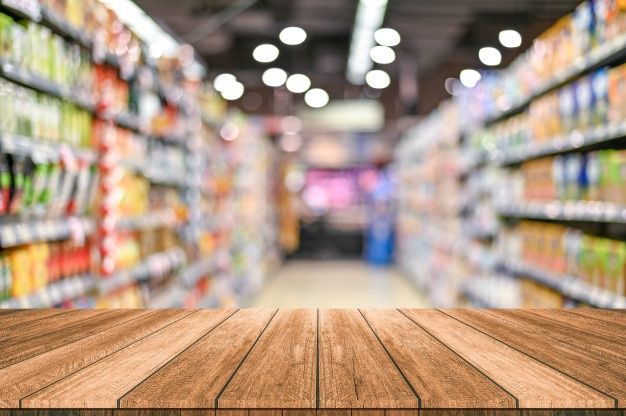 a wooden table top in front of a store aisle filled with drinks and sodas