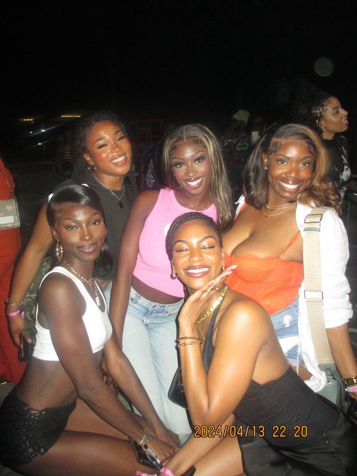 a group of young women posing for a photo in front of a crowd at night