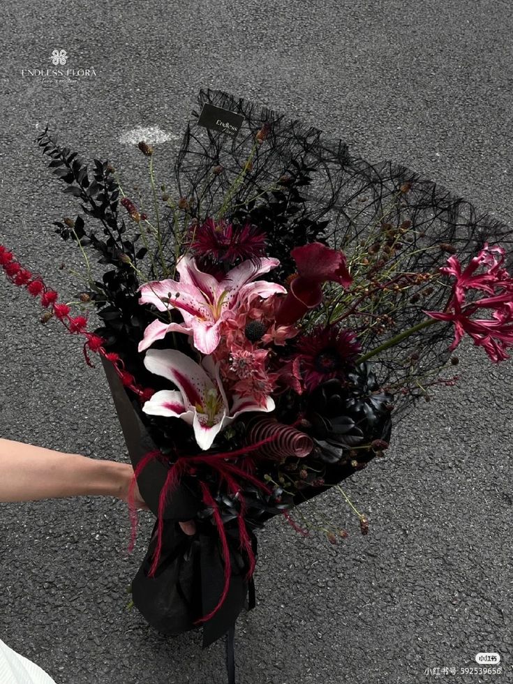 a bouquet of flowers sitting on the ground next to a person's hand holding it