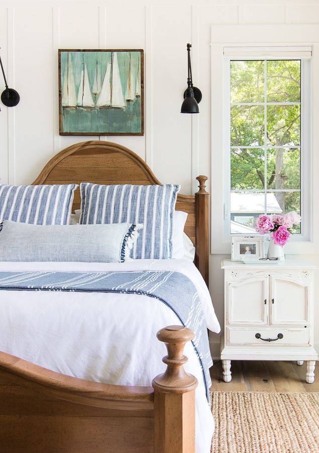 a bed with blue and white pillows in a bedroom next to a window that has pictures on the wall above it