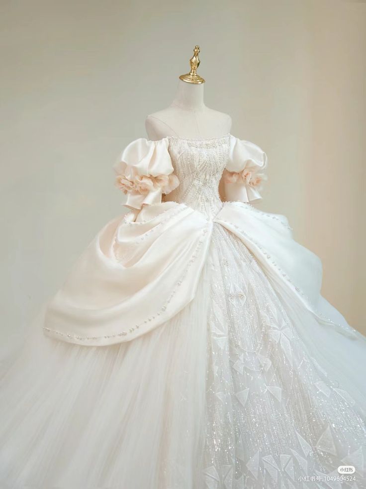 a white wedding dress with pink flowers on the bustle and sleeves is displayed in front of a mannequin