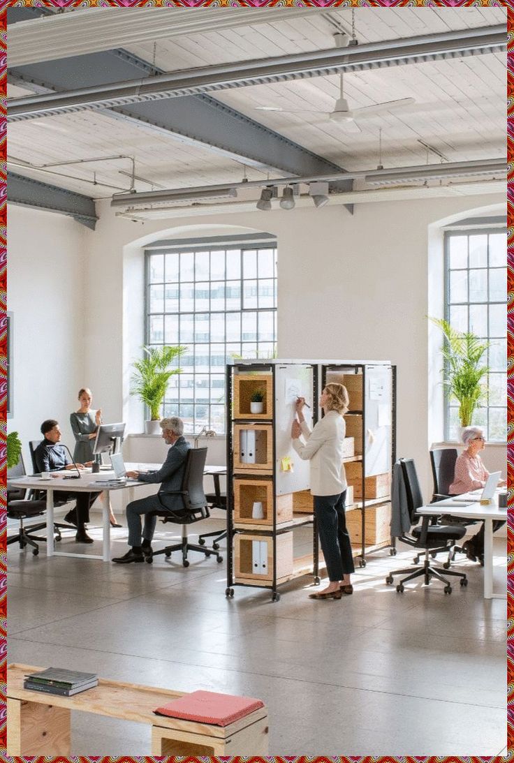 an office with people working on their desks and in the background is a red frame