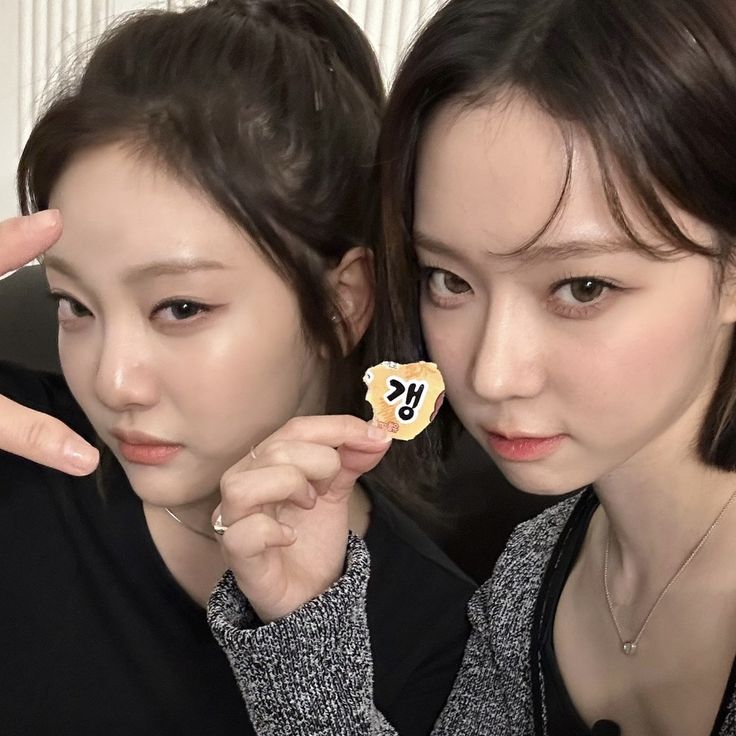 two young women holding up small cookies with the word love spelled on them