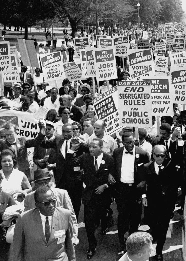 a large group of people holding signs and walking down the street in black and white