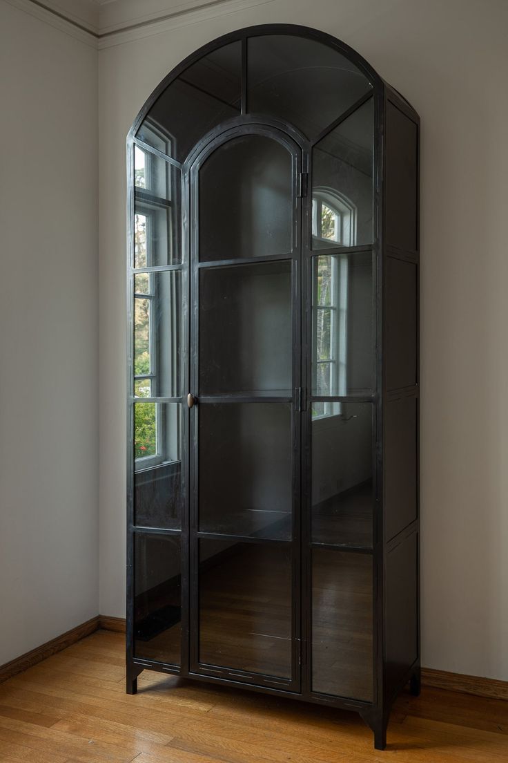 an arched glass cabinet in a room with hardwood floors