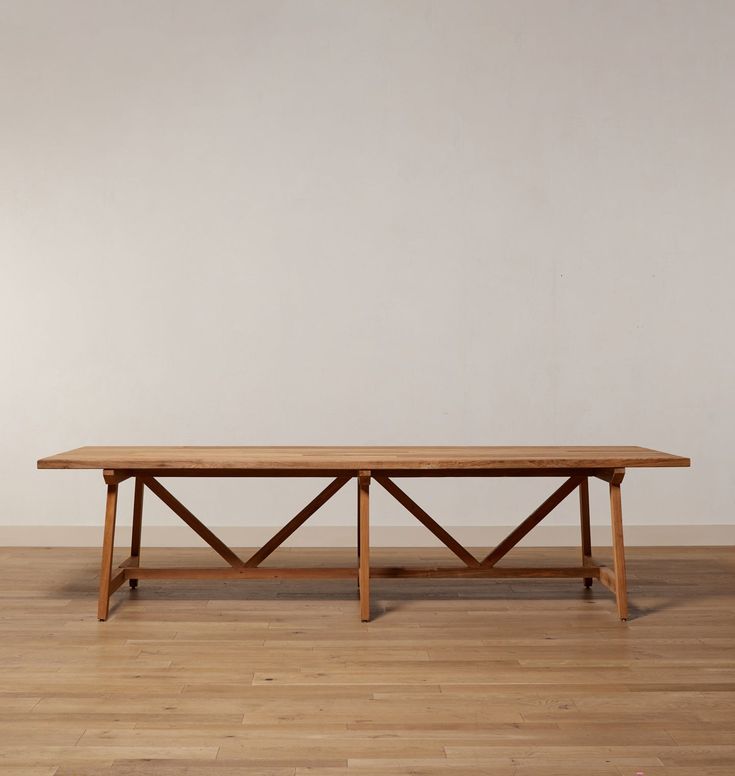 a wooden table sitting on top of a hard wood floor next to a white wall