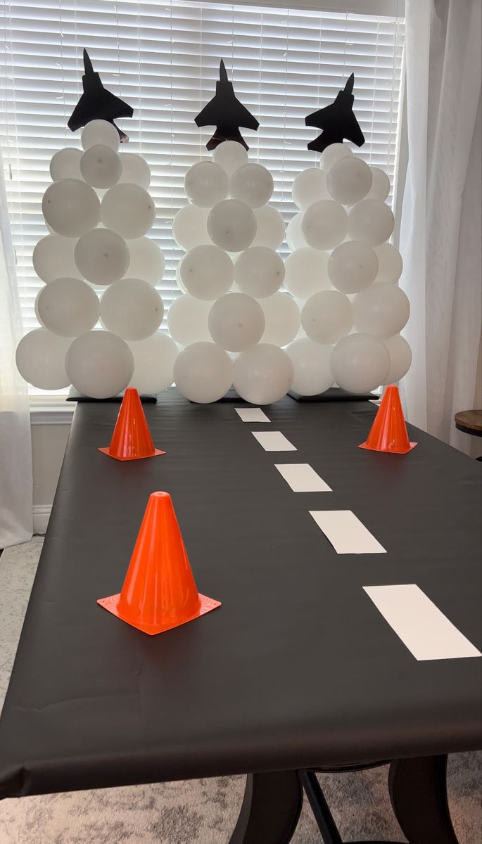 some orange cones sitting on top of a table with balloons in the shape of stars