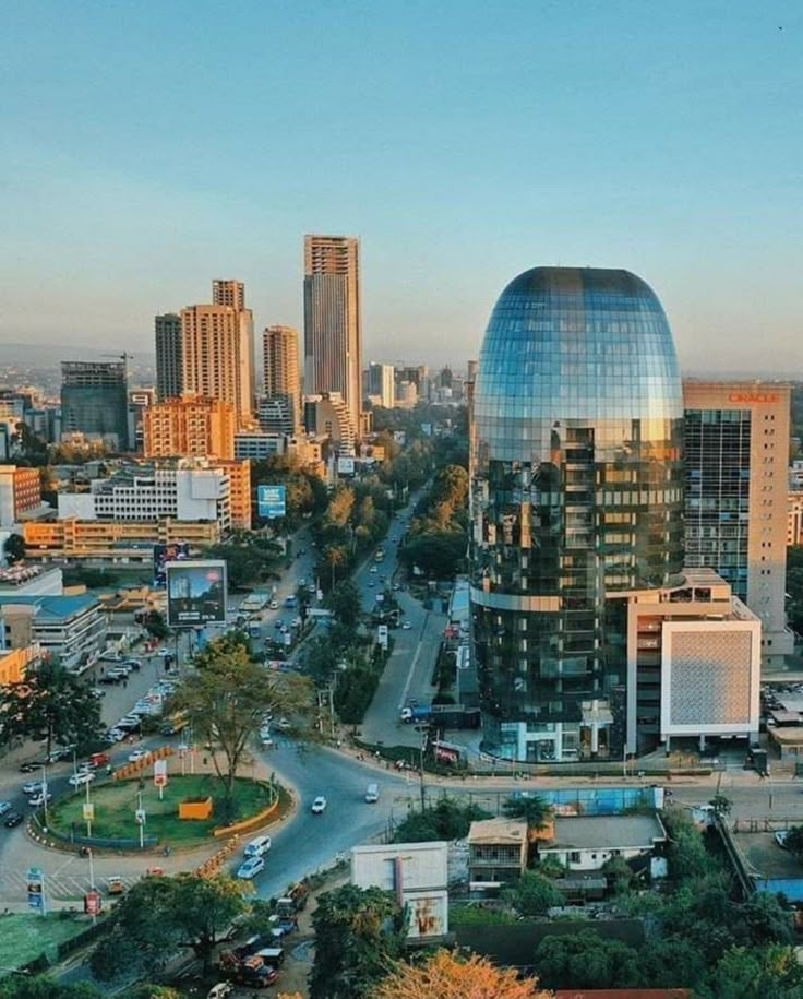 an aerial view of a city with skyscrapers and cars in the foreground at sunset