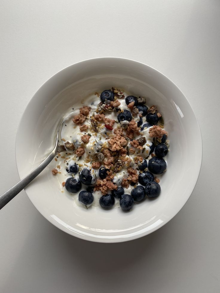 a white bowl filled with cereal and blueberries