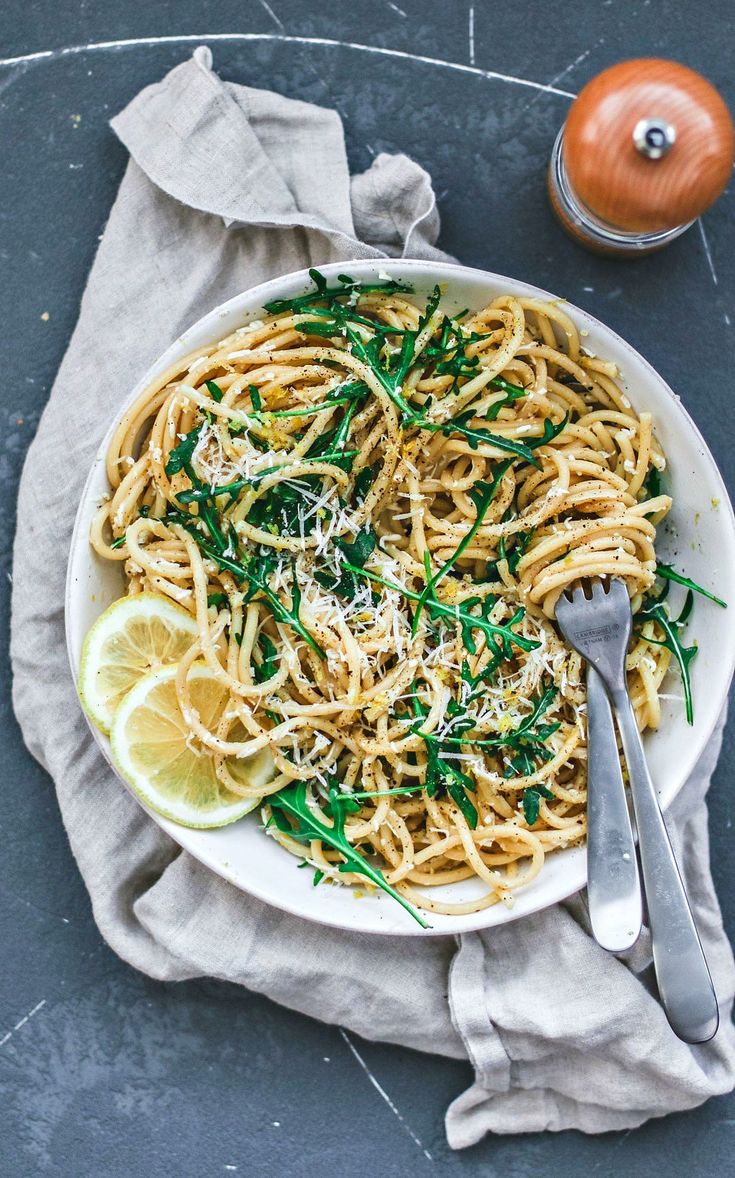 lemon pasta with arugula and parmesan cheese in a white bowl on a gray background