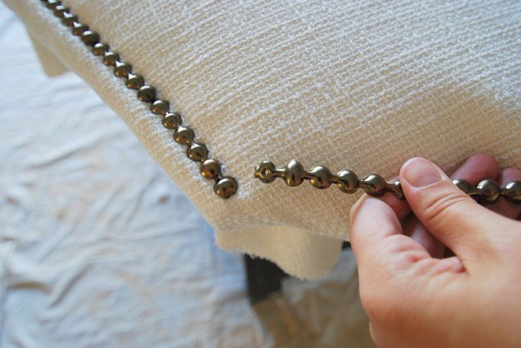 a person holding onto a chain on top of a pillow with gold balls hanging from it