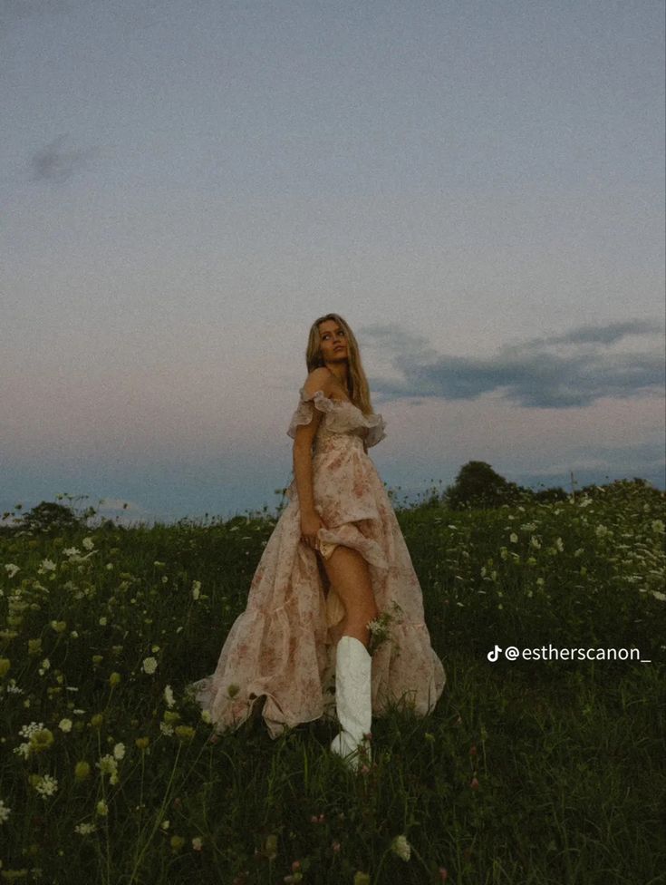 a woman in a dress and boots is standing in the middle of a field with flowers