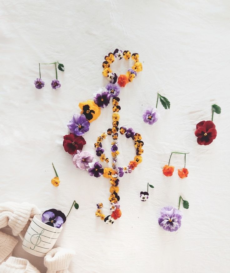 an overhead view of flowers and beads on a white surface with the word peace spelled out