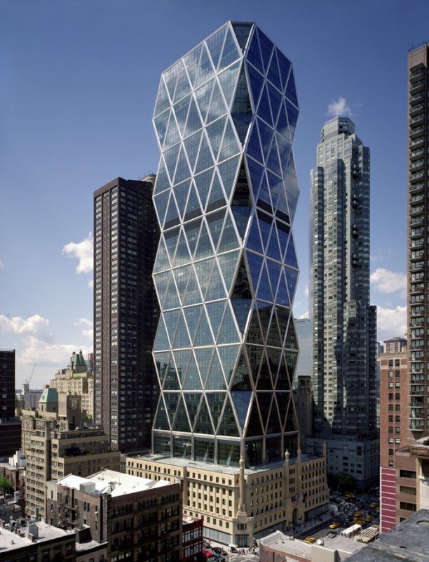 a very tall glass building in the middle of some big cityscape with skyscrapers behind it