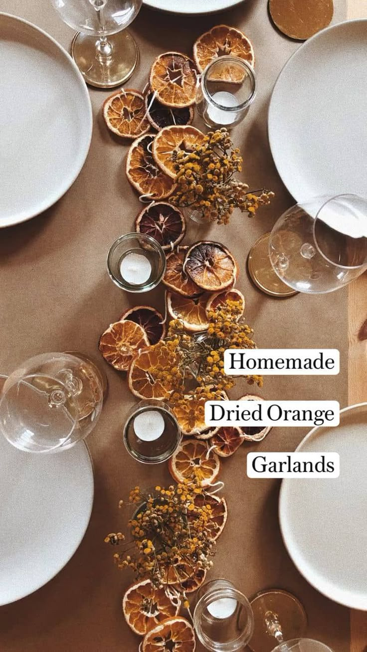 the table is set with oranges and wine glasses on it, along with white plates