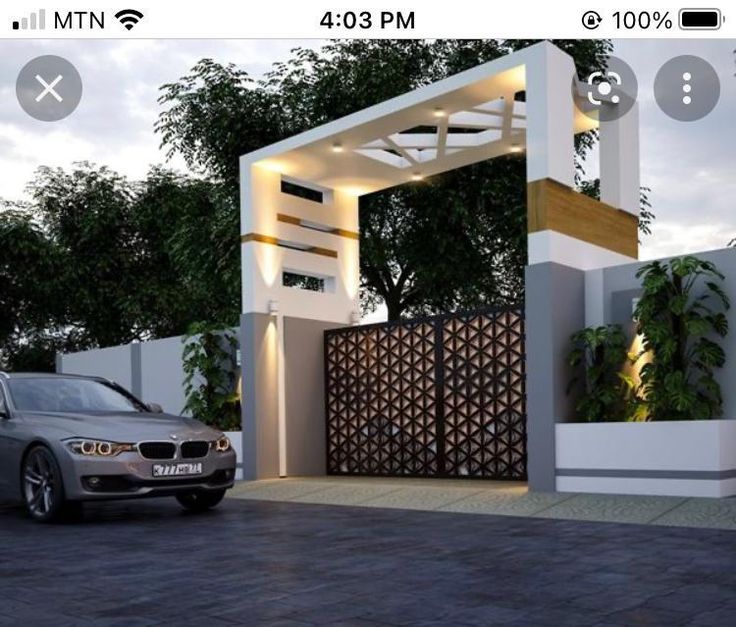 a car is parked in front of a house with a gate and lights on it