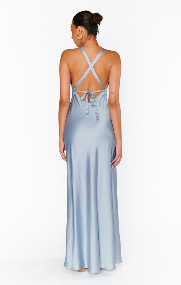 the back of a woman wearing a light blue dress with an open back and cross straps