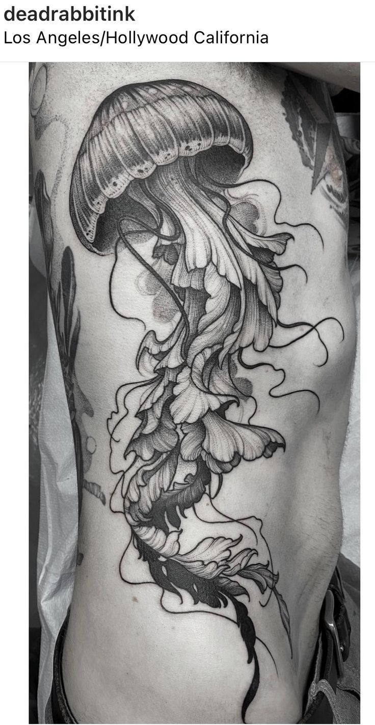 the back of a man's stomach with a jellyfish tattoo on his side