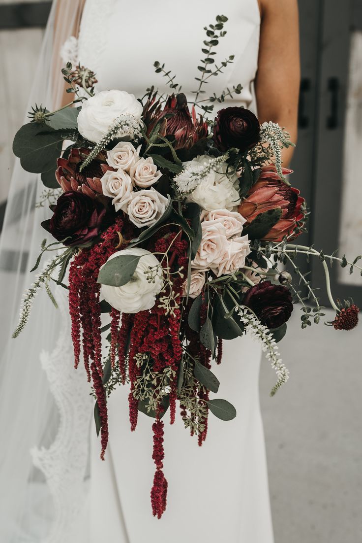 a bride holding a bouquet of flowers and greenery