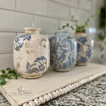 three blue and white vases sitting on top of a counter