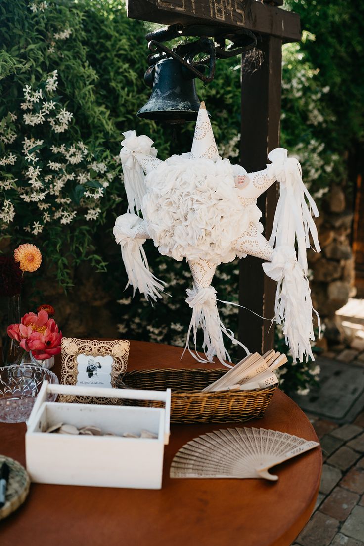 a wooden table topped with white flowers and a bell hanging from it's side